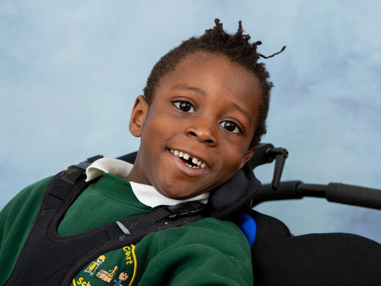 Big smile from this young disabled boy having his accessible school portrait taken in Kent