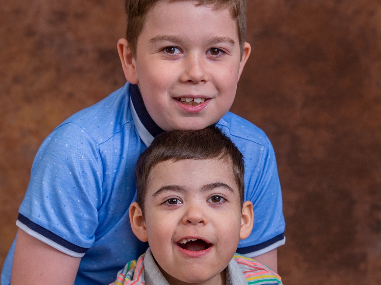A young boy with a medical condition and his older brother having a sibling photograph at Keech Hospice Luton